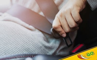 Рука водія присстебує ремінь безпеки в автомобілі.