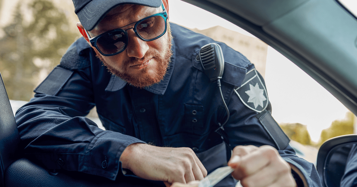 Бородатий поліцейський перевіряє документи у водія занурившись в салон авто